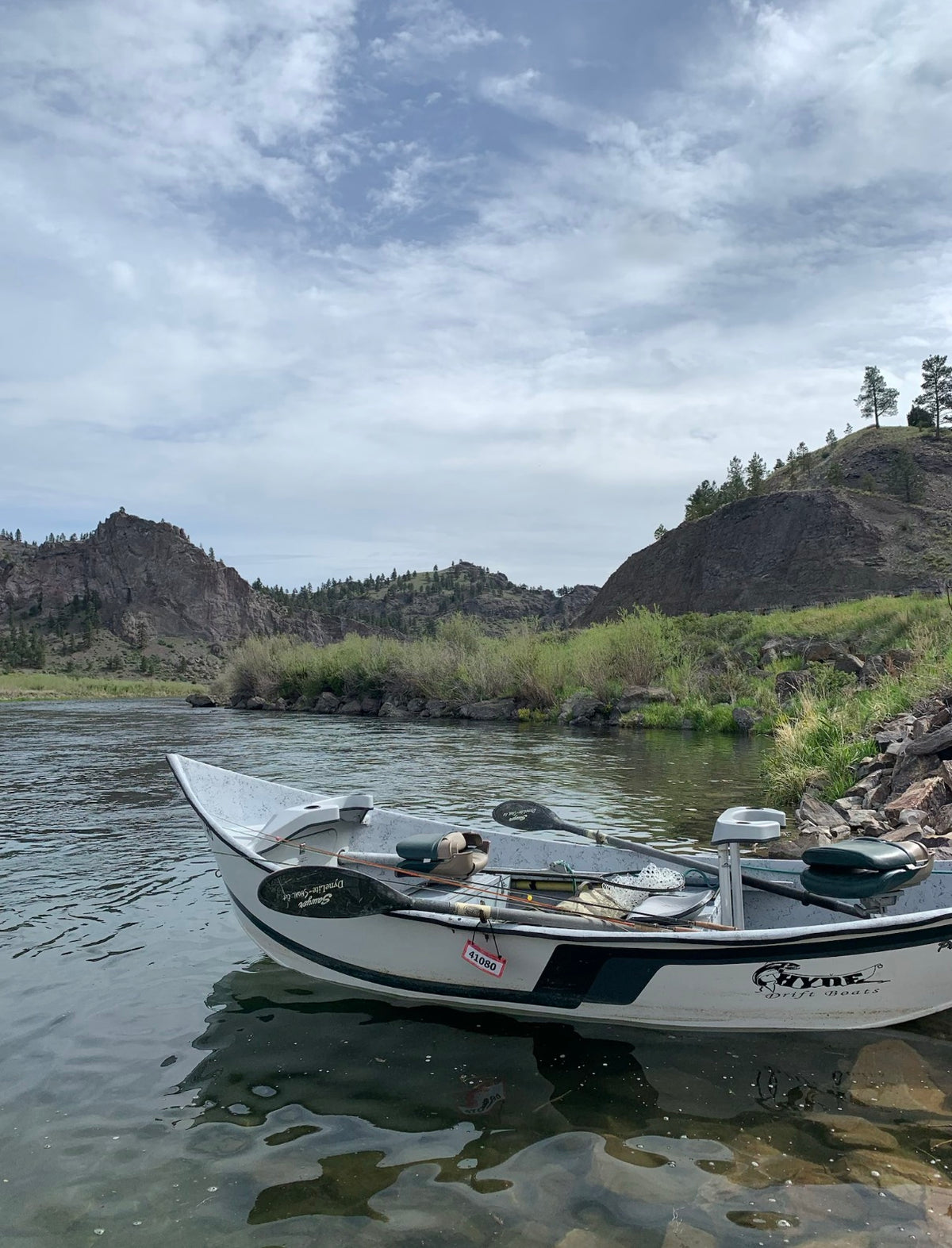 Drift boat anchored along the Missouri River below rocky canyon hills