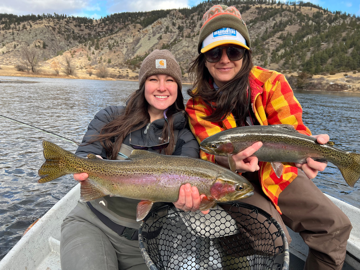 Two anglers in a drift boat each holding a Missouri River rainbow trout